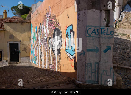 Graffiti an der Wand in der Nähe der kopfsteingepflasterten Gasse im Stadtteil Alfama auf dem Weg bis zum Schloss in Lissabon, Portugal Stockfoto