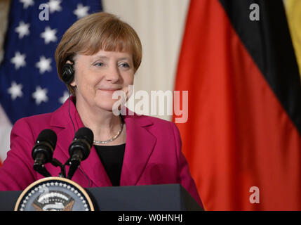 Von den Amerikanischen und deutschen Fahnen flankiert, die deutsche Bundeskanzlerin Angela Merkel lächelt eine Bemerkung bei einer gemeinsamen Pressekonferenz mit US-Präsident Barack Obama im Osten Zimmer im Weißen Haus in Washington, D.C. am 9. Februar 2015. Merkel lächelte, nachdem Obama stellte fest, dass er nicht mit ihr zwei Wochen vor einer Bundestagswahl und würde Sie vermutlich nicht gebeten haben, in Bezug auf die geplanten israelischen Ministerpräsidenten Benjamin Netanjahus Besuch in den Vereinigten Staaten vor den israelischen Wahlen im März erfüllt würde. Foto von Pat Benic/UPI Stockfoto