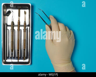 Zahnmedizinische Instrumente in Fach und Zahnarzt hand auf blauem Hintergrund Stockfoto