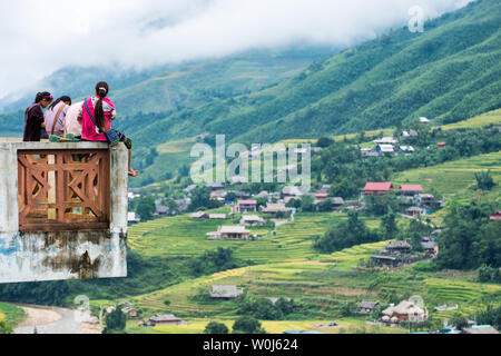 Sapa, Vietnam - Sep 08 2017: Junges Mädchen Stamm Gruppe sitzen auf der Terrasse und Blick auf das Dorf Reis Reihenhaus in Tal Stockfoto