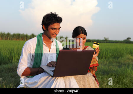 Indischen Bauern tun, Online-shopping mit seiner Frau in einem Feld Stockfoto