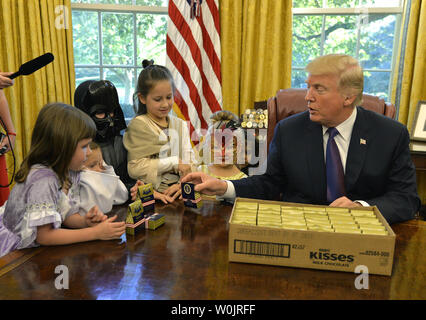 Präsident Donald Trump heraus gibt, Süßigkeit mit dem Presidential Seal als er Kinder begrüßt in Halloween Kostüme, die im Oval Office des Weißen Hauses, Oktober 27, 2017, in Washington, DC. Trump und First Lady Melania Trump willkommen Kinder des Militärs zum Weißen Haus in der nächsten Woche für Halloween Trick - oder - behandeln. Foto von Mike Theiler/UPI Stockfoto