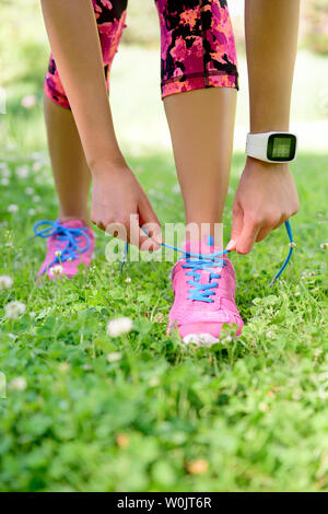 Gewichtsabnahme - runner Schnürsenkel binden tragen smartwatch Wärme- und Activity Tracker für cardio übung. Frau fertig, zum Joggen Workout. Nahaufnahme der Laufschuhe. Stockfoto