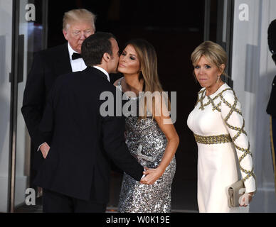 Präsident Donald Trump (L) steht wie der französische Präsident Emmanuel Längestrich begrüßt erste Dame Melania Trump mit einem Kuss, als er und seine Frau Brigitte kommen für ein Abendessen im Weißen Haus, April 24, 2018, in Washington, DC. Der galaabend Höhepunkte ein Tag der bilateralen Verhandlungen über den Handel, Iran, Klimawandel, Nordkorea, Russland unter anderem. Foto von Mike Theiler/UPI Stockfoto