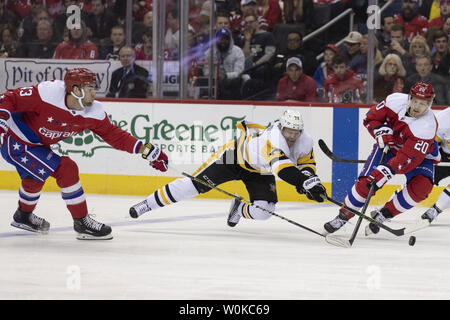 Pittsburgh Penguins rechten Flügel Patric Hornqvist (72) Tauchgänge für einen losen Kobold, während durch die Washington Capitals rechten Flügel Tom Wilson verteidigt (43) und den Hauptstädten center Lars Eller (20) während der zweiten Periode am Kapital einer Arena in Washington, D.C. am 19. Dezember 2018. Foto von Alex Edelman/UPI Stockfoto