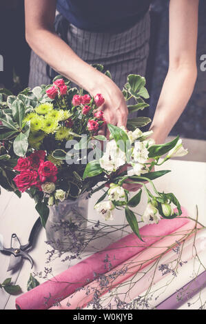 Blumengeschäft arbeitet. Frauenhände, eine Hochzeit Strauß Rosen. Small Business Konzept. Vertikaler Dampfstoß Stockfoto