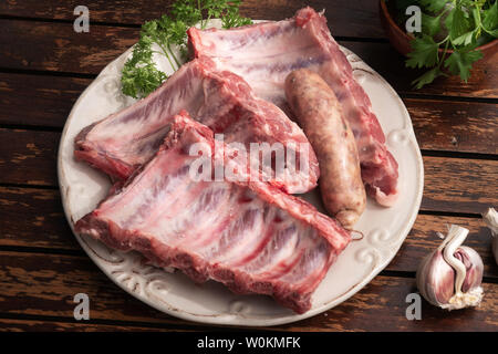 Frische Schweinerippchen und Criollo Wurst auf hölzernen Tisch bereit am Grill zubereitet werden. Spanisch Churrasco Stockfoto