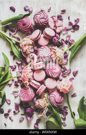 Süße rosa Macarons, Marshmallows und Frühlingsblumen auf hölzernen Hintergrund Stockfoto