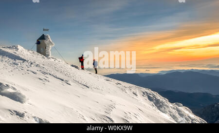 Zwei Alpinisten auf der Oberseite der Berg Triglav. Aussicht auf den Sonnenuntergang. Winter in Slowenien, Europa. Stockfoto