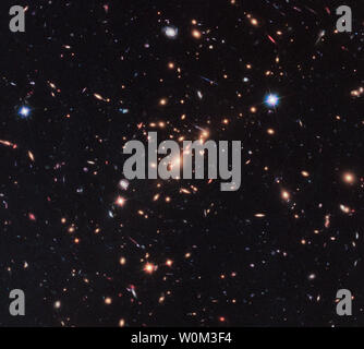 Fungiert als ein "natürliches Teleskop" im Raum und die Schwerkraft von der massiven Vordergrund Galaxienhaufen MACS J2129-0741 vergrößert, erhellt und verzerrt die weit entfernten Hintergrund Galaxie MACS2129-1 in der oberen rechten Ecke des Bildes, veröffentlicht am 23. Juni 2017. Durch die Kombination der Leistung dieser "natürlichen Linse" im Raum mit der Fähigkeit des Hubble-Weltraumteleskop der NASA, Astronomen einer überraschenden Entdeckung - das erste Beispiel für ein kompaktes und dennoch massiv, schnell drehenden, scheibenförmige Galaxie, die aufgehört, Sterne nur wenige Milliarden Jahre nach dem Urknall. Suche nach solch einer Galaxie früh in der histor Stockfoto