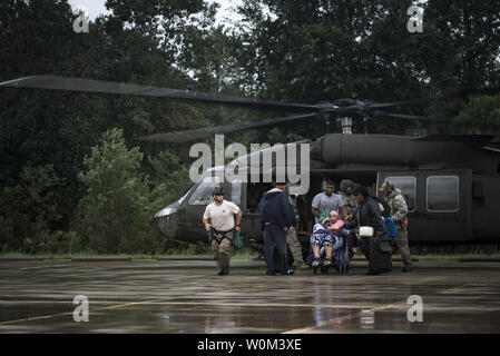 Flieger und Soldaten helfen, Opfer aus einem UH-60 Black Hawk, der am 30. August 2017, im Orange County Convention und Expo Center in Orange, Texas. Die 347 und 563 d Rettung Gruppen von Moody Air Force Base, Ga, Nellis AFB, Nev, und Davis Montana AFB, Ariz., schickte Rettung Boot Mannschaften zu Orange County, Texas, und die umliegenden Bereiche zur Unterstützung der FEMA während des Hurrikans Harvey Disaster Response Bemühungen. Foto: Staff Sgt. Ryan Callaghan/U.S. Luftwaffe/UPI Stockfoto