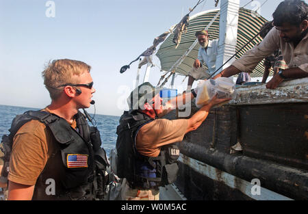 Schiff an Bord Durchsuchung und Beschlagnahme (VBSS) Teammitglieder aus der Lenkwaffen-kreuzer USS Leyte Gulf (CG55) geben Obst und Brot zu einem lokalen Fischerei dhow Crew nach der Durchführung einer Suche des Schiffes im Golf von Oman, am 3. Mai 2004. (UPI Foto/Bart Bauer/US-Navy) Stockfoto