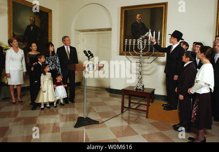 In den letzten drei Jahren, hat der Präsident in einem Menorah lighting vor der jährlichen Weiße Haus Hanukkah Empfang teilgenommen. Am Recht, Menachem Felzenberg leuchtet die Chanukah Menorah als seine Geschwister, Chaim, und Miriam Blick auf drei der sechs Felzenberg Kinder. Auf der linken Seite sind Usa-Präsident George W. Bush und First Lady Laura Bush mit dem Rest der Felzenberg Familie. Ihr Vater, Kapitän Shmuel Felzenberg, dient im Irak als der ältere jüdische Kaplan mit 84Th der US Army Engineer Battalion, von Schofield Kasernen, Hawaii. Stockfoto