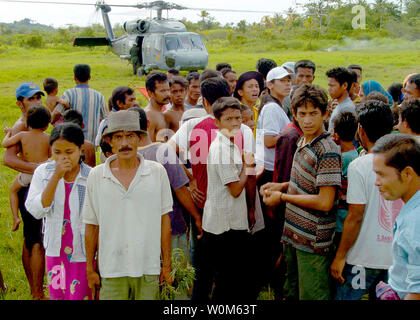 Gestrandet indonesischen Bürger sammeln in der Nähe eines Landeplatzes für eine SH-60F Seahawk Hubschrauber zum "goldenen Falken" der Hubschrauber Anti-Submarine-Staffel Zwei zugewiesenen am 3. Januar 2005 in der Provinz Aceh, Indonesien. (UPI Foto/Gabriel Piper/USN) Stockfoto