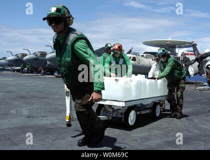 Flight Deck personal Transport eine Waffen skid Voller gereinigtes Trinkwasser zu einem Warten auf SH-60B Seahawk Hubschrauber, zugeordnet zu den aberhawks" der Hubschrauber Anti-Submarine Squadron Licht Vier Sieben (HSL-47), die an Bord der USS Abraham Lincoln (CVN 72) am 31.01.10, 2005, im Indischen Ozean. Hubschrauber Carrier Air Wing Zwei (CVW-2) und Matrosen von Abraham Lincoln zugeordnet sind, unterstützt den Betrieb von Unified Hilfe, humanitäre Hilfe Aufwand im Zuge der Tsunami, der Südostasien heimgesucht. (UPI Foto/Tyler J. Clements/US-Navy) Stockfoto