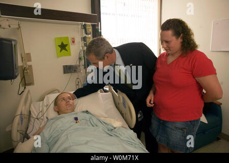 Präsident George W. Bush klopft dem Leiter der Pvt. 2. Klasse Bart Tucker von Sioux City, Iowa, Freitag, 1. Juli 2005, während seine Frau Heather schaut an. Ê Der Präsident besucht der Soldat am Walter Reed Army Medical Hospital, wo er Pvt ausgezeichnet. Tucker ein violettes Herz für Verletzungen, die Sie erhalten, während sie im Irak dienen. Ê (UPI Foto/Eric Draper/Weiße Haus) Stockfoto