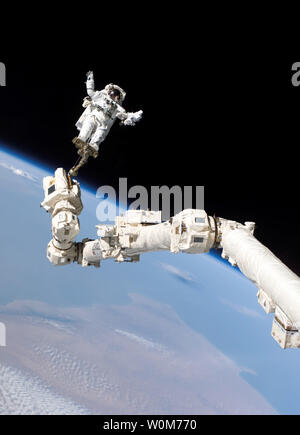 Zu einem Fuß Zurückhaltung auf dem Roboterarm der Internationalen Raumstation verankert, STS-114 Mission Specialist Steve Robinson nimmt an der dritten Außenbordeinsatz der Mission am 5. August 2005. Die Landung der Discovery war 24 Stunden bis August 9, 2005 Wegen schlechten Wetters in Florida. (UPI Foto/NASA) Stockfoto