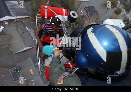 Petty Officer 1st Class Steven Huerta Hebezeuge zwei Kinder in ein Coast Guard Rescue Helicopter in New Orleans am 12.08.29, 2005, nach dem Hurrikan Katrina massive Überflutungen verursacht. Anderen schauen von unten als die Kinder sind unter vielen New Orleans Bürger von ihren Dächern gerettet werden. (UPI Foto/USCG/Kyle Niemi) Stockfoto