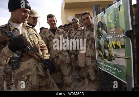 Irakische Soldaten lesen ein Plakat vor dem Wahllokal, da sie in Linie warten zusammen mit anderen irakischen Sicherheitskräfte bei Hayji, Irak zu stimmen, am 12. Dezember 2005. Irakische Bürger stimmen wird am 04.12.15, 2005, der Irak parlamentarische Regierung zu wählen. (UPI Foto/Andy Dunaway/Air Force) Stockfoto