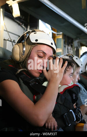 Eine amerikanische Frau beruhigt ein Kind während eines US Marine Corps CH-53 Super Hengst Hubschrauber von der US-Botschaft in Beirut, Libanon fliegen, zu Royal Air Force Base Akrotiri in Zypern am 18. Juli 2006. Auf Antrag der US-Botschafter in Libanon und an der Richtung des Verteidigungsministers, das United States Central Command und 24 Marine Expeditionary Unit sind die Unterstützung bei der Abreise von US-Bürgern aus dem Libanon. Die Hubschrauber sind für Marine Medium Helicopter Squadron 365 befestigt. (UPI Foto/James H. Frank/U.S. Marine Corps) Stockfoto