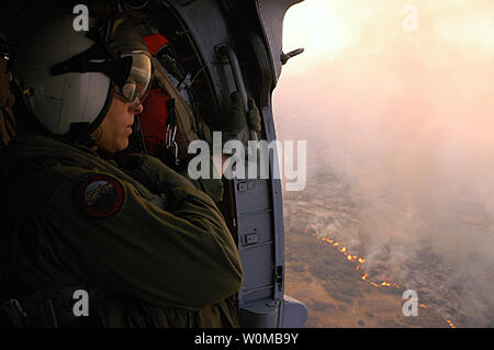 Chief Aviation Electronics Technician Rexford Sackett, Hubschrauber Meer Combat Squadron (HSC) 85 zugewiesen, schaut auf Meilen von verbrannten Terrain, wie er und andere Segler vorbereiten, um die Flamme an Bord eines MH-60S Seahawk in San Diego am 23. Oktober 2007. Die Flamme hat bereits mehr als 250.000 Menschen aus ihren Häusern vertrieben. (UPI Foto/Chris Fahey/USN) Stockfoto