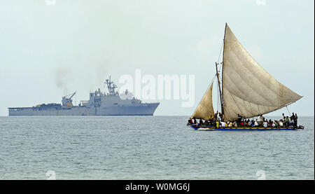 Eine haitianische Boot segelt an der Küste von Haiti am 19. Januar 2010 Als amphibische Landung dock Schiff USS Carter Hall (LSD 50) betreibt in der Ferne. Carter Hall unterstützt den Betrieb einheitliche Reaktion, eine gemeinsame Operation humanitäre Hilfe nach einem Erdbeben der Stärke 7.0, dass die Insel Nation Jan. 12, 2010 verwüstet. UPI/Kristopher Wilson/USA Marine Stockfoto