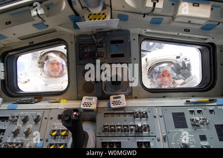 Astronauten Michael Good (L) und Garrett Reisman Blick durch die aft Flight Deck Windows des Space Shuttle Atlantis während der dritten Außenbordeinsatz der Mission am 21. Mai 2010. Während des spacewalk, Gut und Reisman beendet die Installation der letzten zwei der sechs neue Batterien für die B-Seite von Port 6 solar array. Darüber hinaus werden die Astronauten installiert ein backup Ammoniak Überbrückungskabel zwischen Anschluss 4 und 5 Traversen der Station und Übertragen der Daten- und Vorrichtung von der Shuttle zum Bahnhof auseinander. UPI/NASA Stockfoto