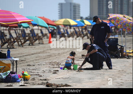 Petty Officer 1st Class Matt Fisher, kniend, und Petty Officer 1st Class James Huddleston, Marine science Techniker bei Coast Guard Sektor C Houston Galveston, prüfen eine mögliche Tarball auf der Stewart Beach als Strandurlauber, in Galveston, Texas, am 11. Juli 2010. Staatlichen, lokalen und föderalen Beamten haben Patrouillen entlang der Texas Küste als Reaktion auf Berichte über Tarballs waschen an Land gestiegen. UPI/Prentice Danner/U.S. Küstenwache Stockfoto