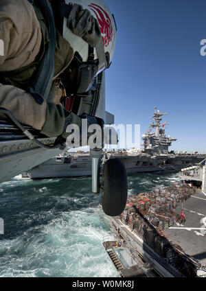 U.S. Navy Naval Air Crewman 2. Klasse Cory Merritt, zugeordnet zu den Hubschrauber Anti-Submarine Squadron (HS) 15, führt den Piloten eines HH-60H Seahawk Hubschrauber, wie sie die Ladung von der schnellen Combat support ship USNS Brücke während eine Auffüll-anforderung auf See abrufen mit dem Flugzeugträger USS Carl Vinson im Persischen Golf März 6, 2012. Carl Vinson und Carrier Air Wing 17 wurden in die USA 5 Flotte Verantwortungsbereich eingesetzt. UPI/James R. Evans/U.S. Marine Stockfoto