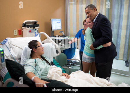 Präsident Barack Obama umarmt Stephanie Davies, die dazu beigetragen, ihr Freund, Allie Junge, Links, lebendig, nachdem sie während des Films Aurora Kino Schießereien in Aurora, Colorado, 22. Juli 2012 erschossen wurde. UPI/Pete Souza / White House Stockfoto