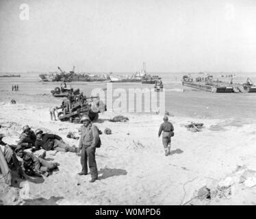 Szene auf einem der Invasion Strände, während Kraft Anhaftungen Operationen im Juni 1944. Hinweis: Shore party Entspannen (links im Vordergrund); Bulldozer mit schweren Kotflügel auf seine Klinge, evtl. für Boot retten Zwecke (hinter dem Ufer zu); Strände Landung Schiffe, einschließlich (von links nach rechts): USS LCT-852; Britischer LCT-2302 und ein Rhino (rhf) Ponton Barge. Dieses Foto, aufgenommen von Bekämpfung Foto Einheit Elf (CPU-11), wurde von der Marine Foto Science Laboratory am 3. Juli 1944 empfangen. Foto: US Navy/National Archives/UPI Stockfoto