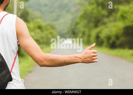 Close up junge Arm und Hand per Anhalter auf Mountain Road. Stockfoto