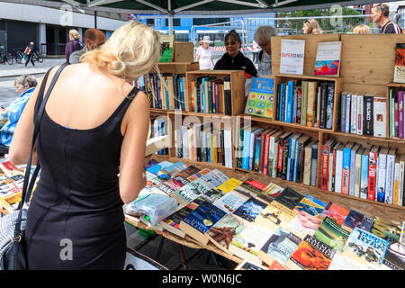 Eine Frau sucht die Titel auf eine zweite-Hand buch Stand beim Markt am Samstag in Navigator Square, Torbogen, nördlich von London, UK, 2019 Stockfoto