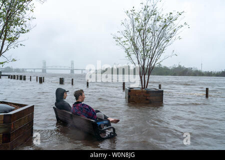 Zach Boucher und Chris Craig sitzen auf einer Bank in den überschwemmten Waters Edge nach dem Hurrikan, jetzt Tropischer Sturm Florenz September 14, 2018 in der Innenstadt von Wilmington, North Carolina. Foto von Ken Cedeño/UPI Stockfoto