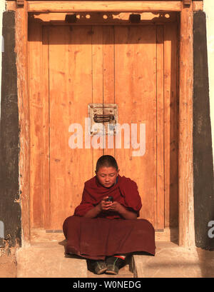 Eine youngTibetan Mönch spielt mit seinem Handy Labrang Kloster, das größte tibetische Kloster außerhalb von Lhasa, vor der tibetischen Monlam Festival in Xiahe, Gansu Provinz auf dem tibetischen Plateau, 2. Februar 2012. Zehntausende Tibeter feiern die tibetischen Neujahr durch ihren Weg zu dieser Stadt und ihrer Labrang Kloster, deren Trennung von der Autonomen Region Tibet stellt eine Maßnahme für den Schutz von Han-chinesischen Versuche, ihre Kultur zu regulieren. UPI/Stephen Rasierer Stockfoto