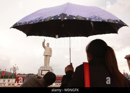 Chinesische Touristen fotografieren vor einer der wenigen verbliebenen öffentlichen Satzung der späten Steuermann Mao Zedong in ein Quadrat in Lijiang, nördliche Yunnan Provinz, am 29. September 2012. Während der Kulturrevolution unter der Roten Garde, Maos bereits verherrlicht Bild in einem Personenkult, die jeden Aspekt der chinesischen Lebens beeinflusst offenbarte, und weiterhin besteht zu über dem Land. UPI/Stephen Rasierer Stockfoto