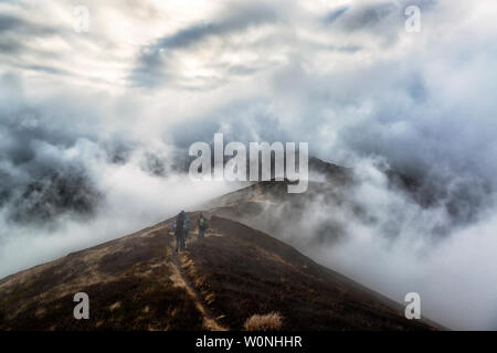 Wanderer auf einem Höhenweg mit dramatischen Wolken herum und unten. Karpaten, Ukraine Stockfoto