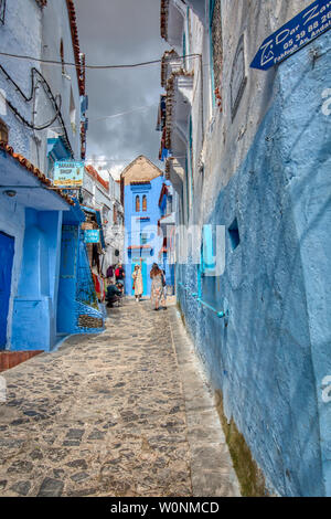 Chefchaouen, Marokko - Mai 03, 2019: Traditionelle Straße von Chefchaouen, wo man sehen kann asiatische Touristen Bilder im Hintergrund unter Stockfoto