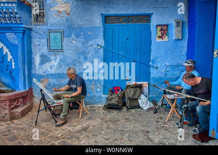 Chefchaouen, Marokko - Mai 03, 2019: asiatische Touristen Malerei Bilder auf einer wunderschönen Straße in der touristischen Stadt Chefchaouen in Nordmarokko Stockfoto