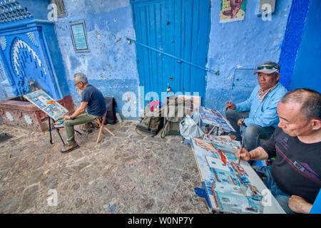 Chefchaouen, Marokko - Mai 03, 2019: asiatische Touristen Malerei Bilder auf einer wunderschönen Straße in der touristischen Stadt Chefchaouen in Nordmarokko Stockfoto