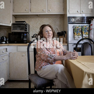 Eine ältere Frau sitzt in Ihrem altmodischen Küche Stockfoto