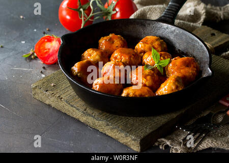Hausgemachte Frikadellen mit Gewürzen und Tomaten in einer Pfanne auf dunklen Tisch aus Stein. Freier Platz für Ihren Text. Stockfoto