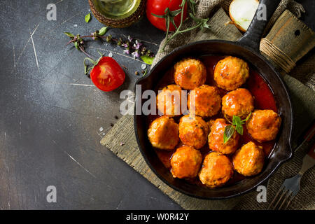 Hausgemachte Frikadellen mit Gewürzen und Tomaten in einer Pfanne auf dunklen Tisch aus Stein. Freier Platz für Ihren Text. Flach, Ansicht von oben Hintergrund. Stockfoto