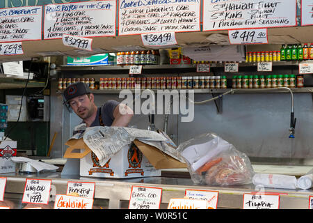 Vereinigte Staaten von Amerika, USA, Seattle, Washington, Pike Place, 10. Mai 2019. Verkäufer Verpackung von frischem Fisch in den öffentlichen Markt steht verkaufen Stockfoto