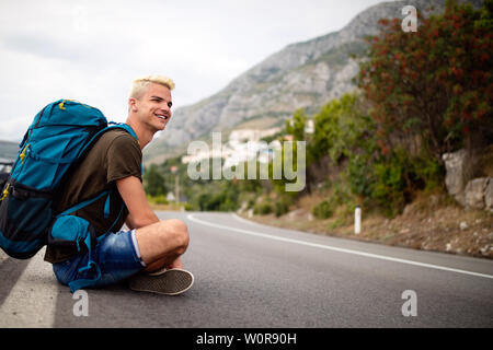 Reisen Mann backpacking per Anhalter auf Straße Reise hitching eine Fahrt aus dem Auto Stockfoto