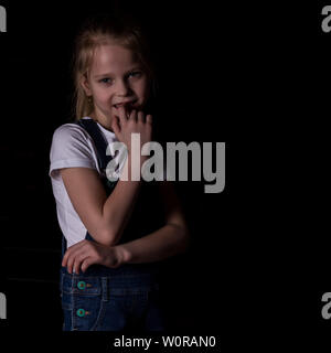 Schöne blonde Mädchen auf einem dunklen Hintergrund. Sie steht in unterschiedlichen Posen und zeigt verschiedene Gefühle. Stockfoto