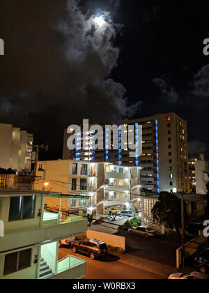 Vollmond hinter den Wolken in Honolulu Makiki und Stadtbild hoch oben am Abend mit Häusern und modernen Hochhäusern, und andere kleine Gebäude. Stockfoto