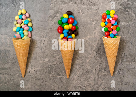 Waffel Hörner mit farbigen Süßigkeiten auf einem Stein. Ansicht von oben, Bonbons und Süßigkeiten Konzept. Stockfoto