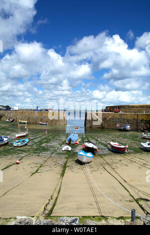 Direktem Blick auf den Hafen von Mousehole in Cornwall (UK) mit Boote am Strand bei Ebbe und unter einem sonnigen Sommer Himmel mit einigen Wolken. Stockfoto