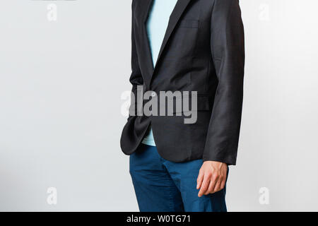 Zugeschnittenes Bild von einem Mann in einem T-Shirt, Hose und eine schwarze Jacke auf grauem Hintergrund. Porträt eines modernen Geschäftsmann. Stockfoto